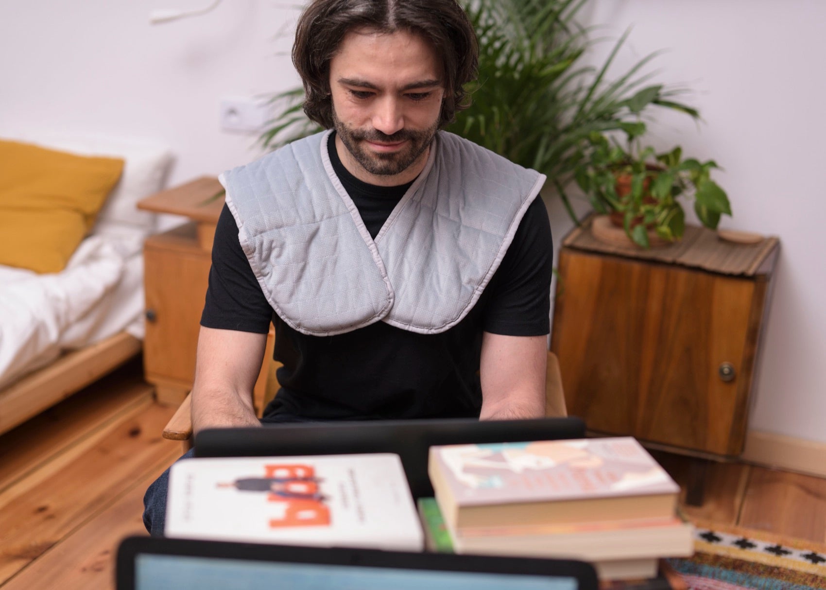 Homme portant un collier lesté sur les épaules en lisant à son bureau