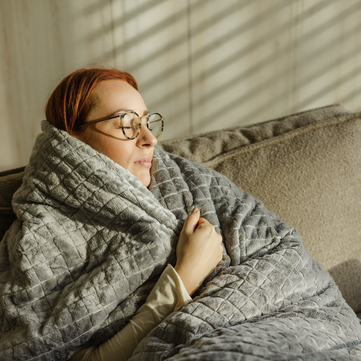 Moment cocooning sur le canapé dans une couverture lestée en peluche grise