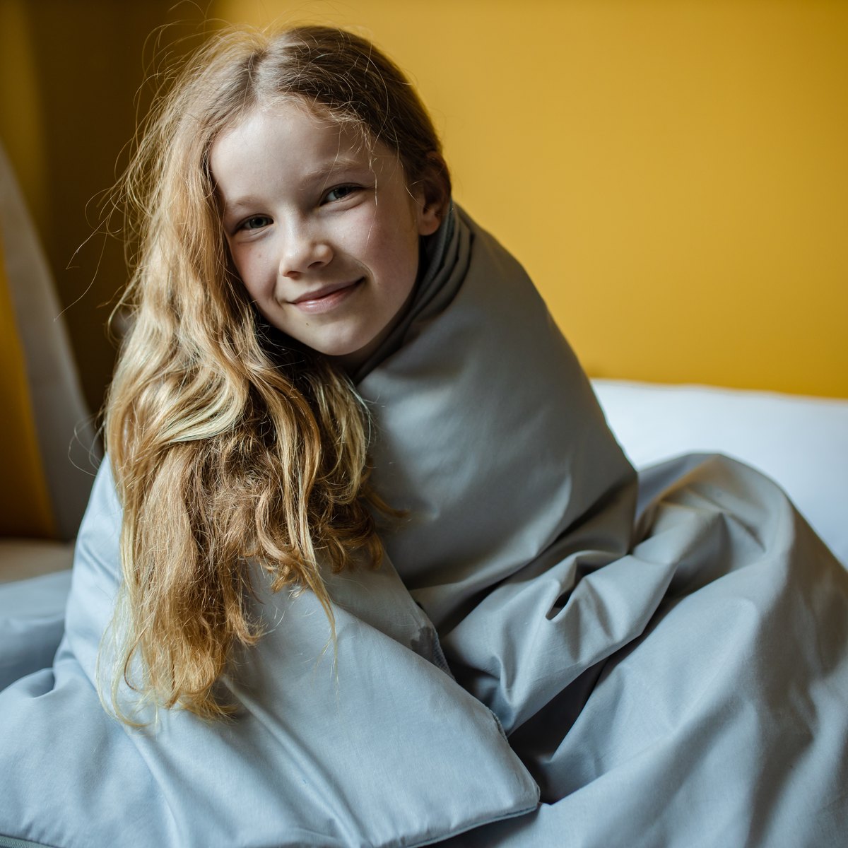 Fillette souriante enveloppée dans une couverture lestée grise