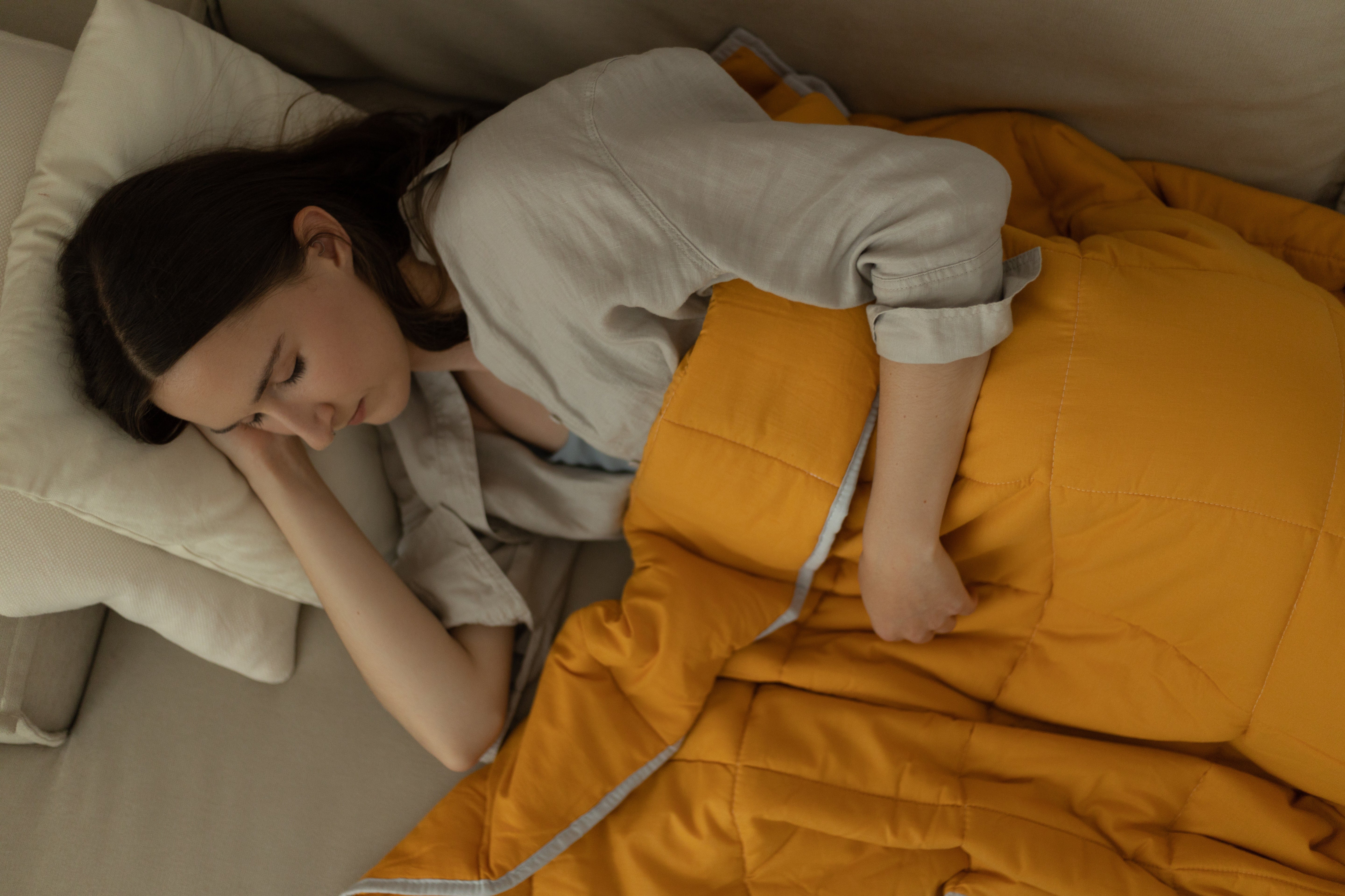 Couverture lestée toutes saisons réversible grise et jaune sur un lit