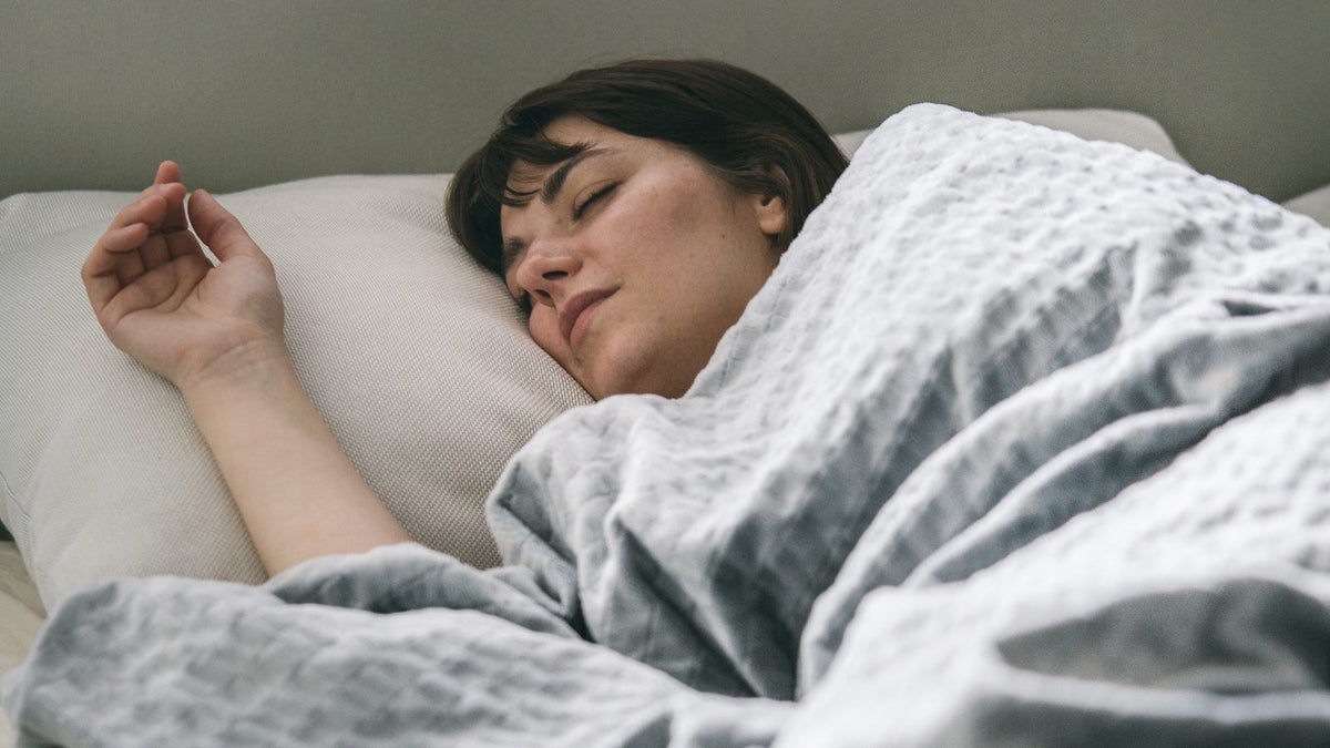Femme endormie sous une couverture lestée grise, douleurs de fibromyalgie apaisées