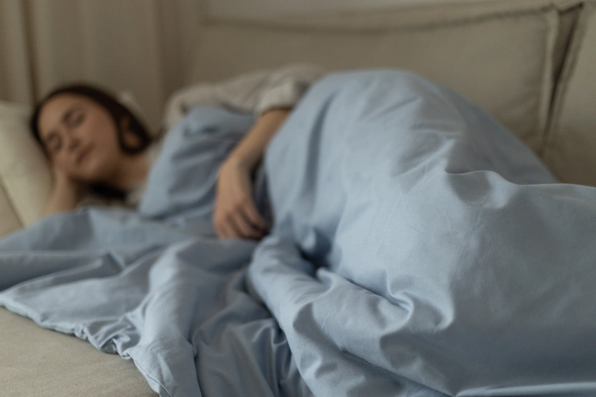 Femme endormie paisiblement sous une couette lestée bleue