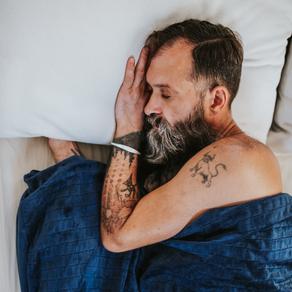 Homme endormi paisiblement sous une couverture lestée bleu marine