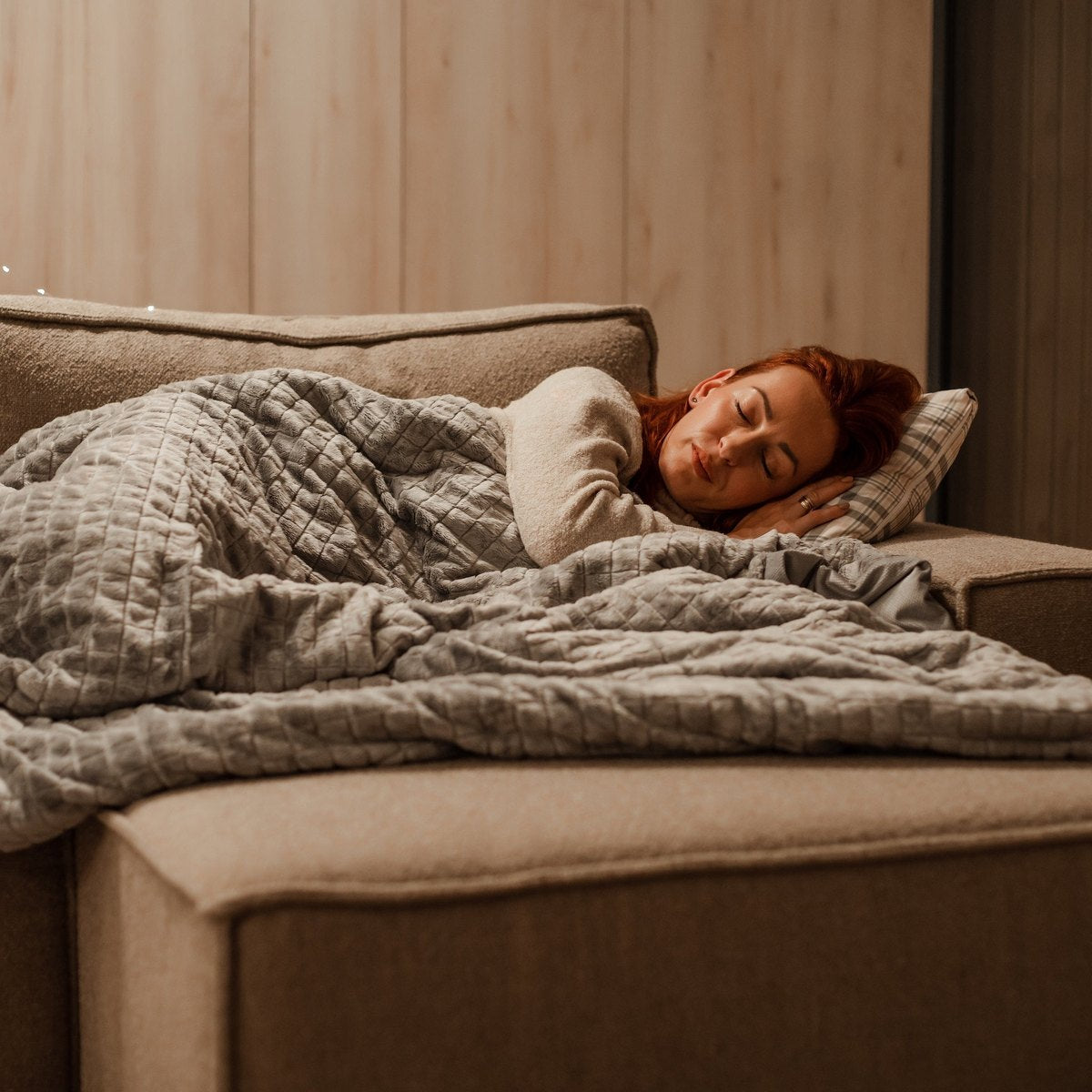 Femme endormie sous une couverture lestée dans une chambre chaleureuse