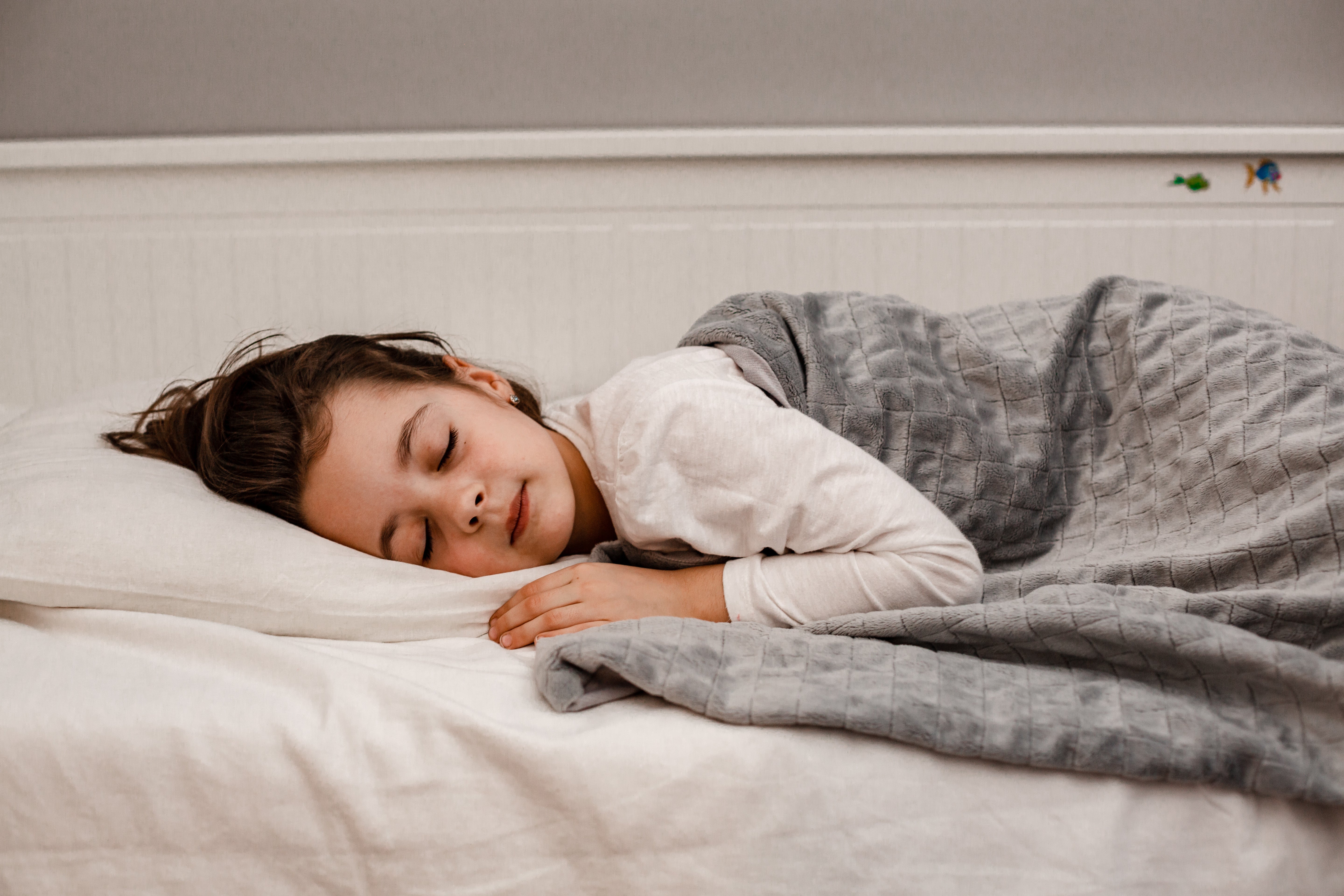 Enfant endormi paisiblement sous une couverture lestée grise