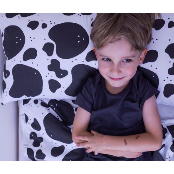 Garçon souriant avec sa housse de couverture lestée motif vaches