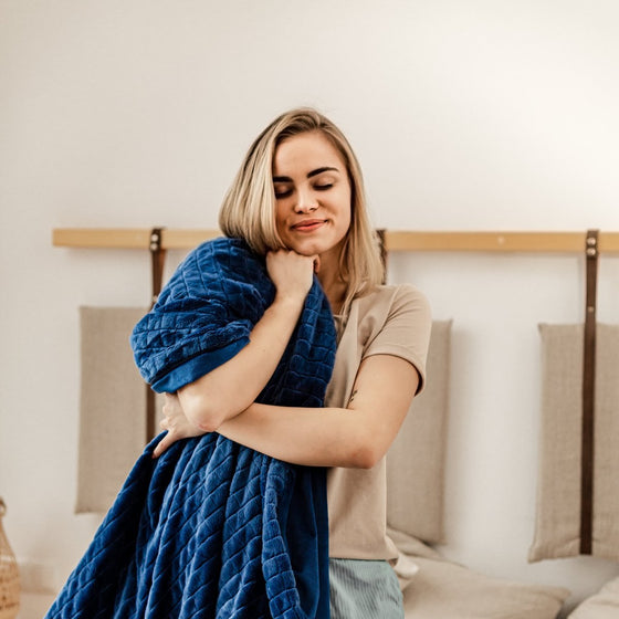 Femme souriante enveloppée dans une couverture lestée en velours bleu