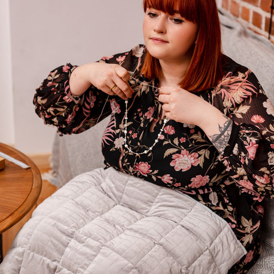Femme détendue au salon avec une couverture lestée sur les genoux