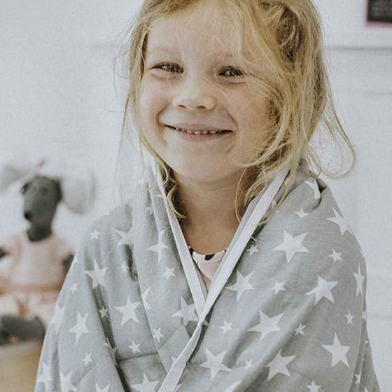 Fillette souriante enveloppée dans une couverture lestée à étoiles
