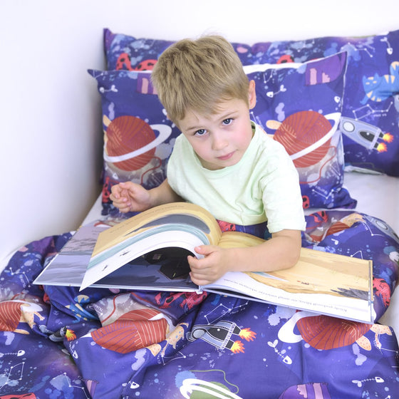 Garçon qui lit un livre sous sa housse de couverture lestée motif espace