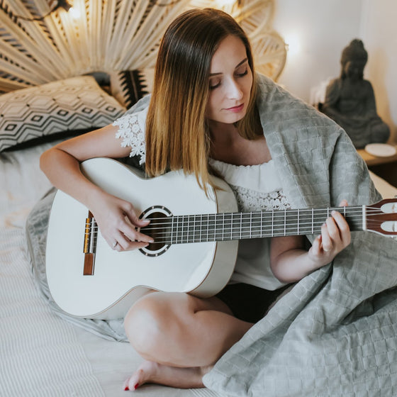 Moment cocooning à la guitare sous une couverture lestée grise