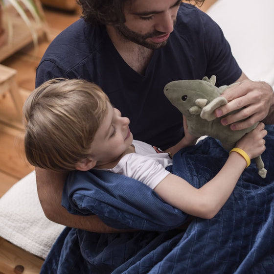 Papa et son fils jouent sous la couverture lestée bleu marine