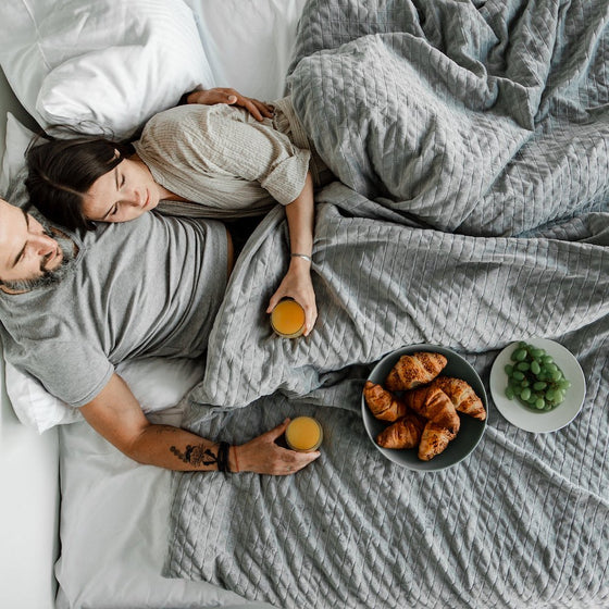Petit déjeuner au lit sous une couverture lestée grise
