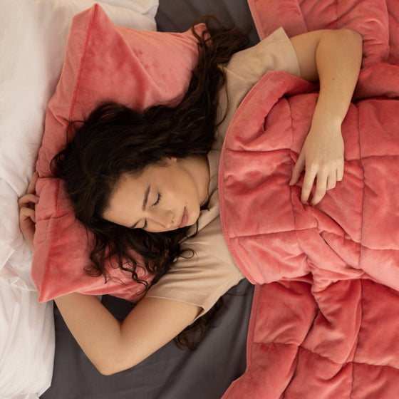 Femme endormie sous une couverture lestée corail
