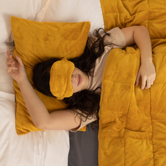 Femme endormie sous une couverture lestée jaune moutarde
