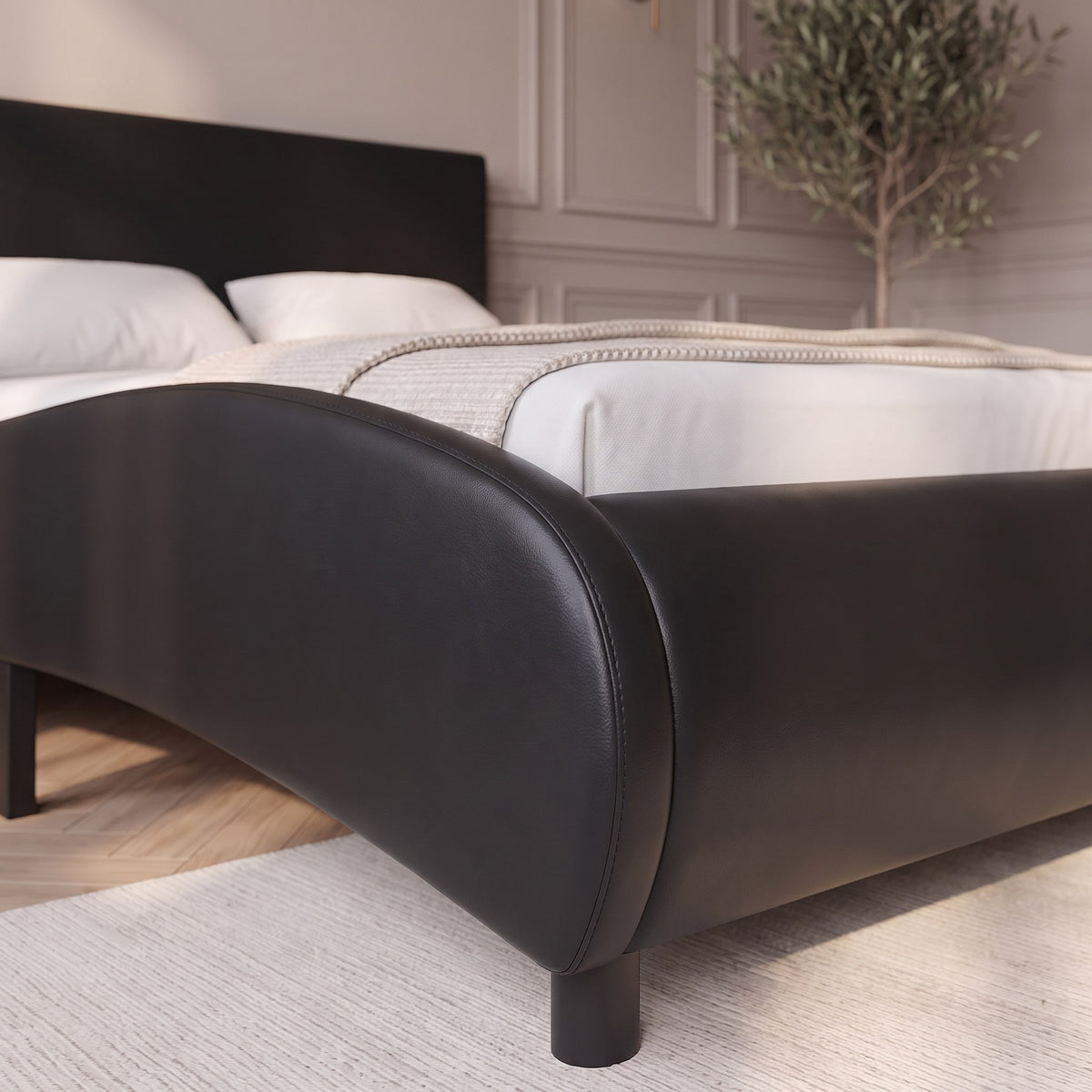 Détail du bout de lit arrondi et rembourré en similicuir noir
